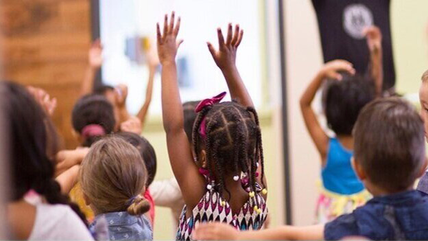 Room of children raising hands